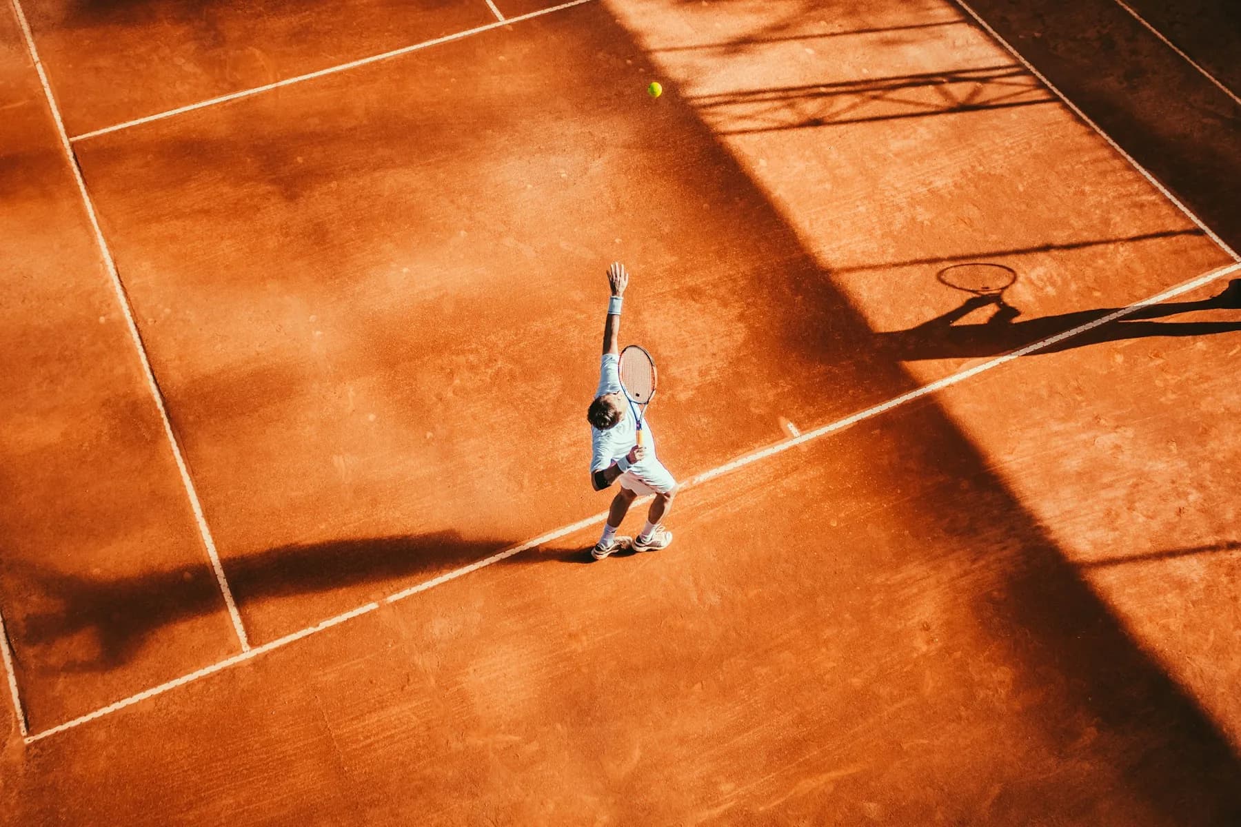 Tennis player serving on a clay court